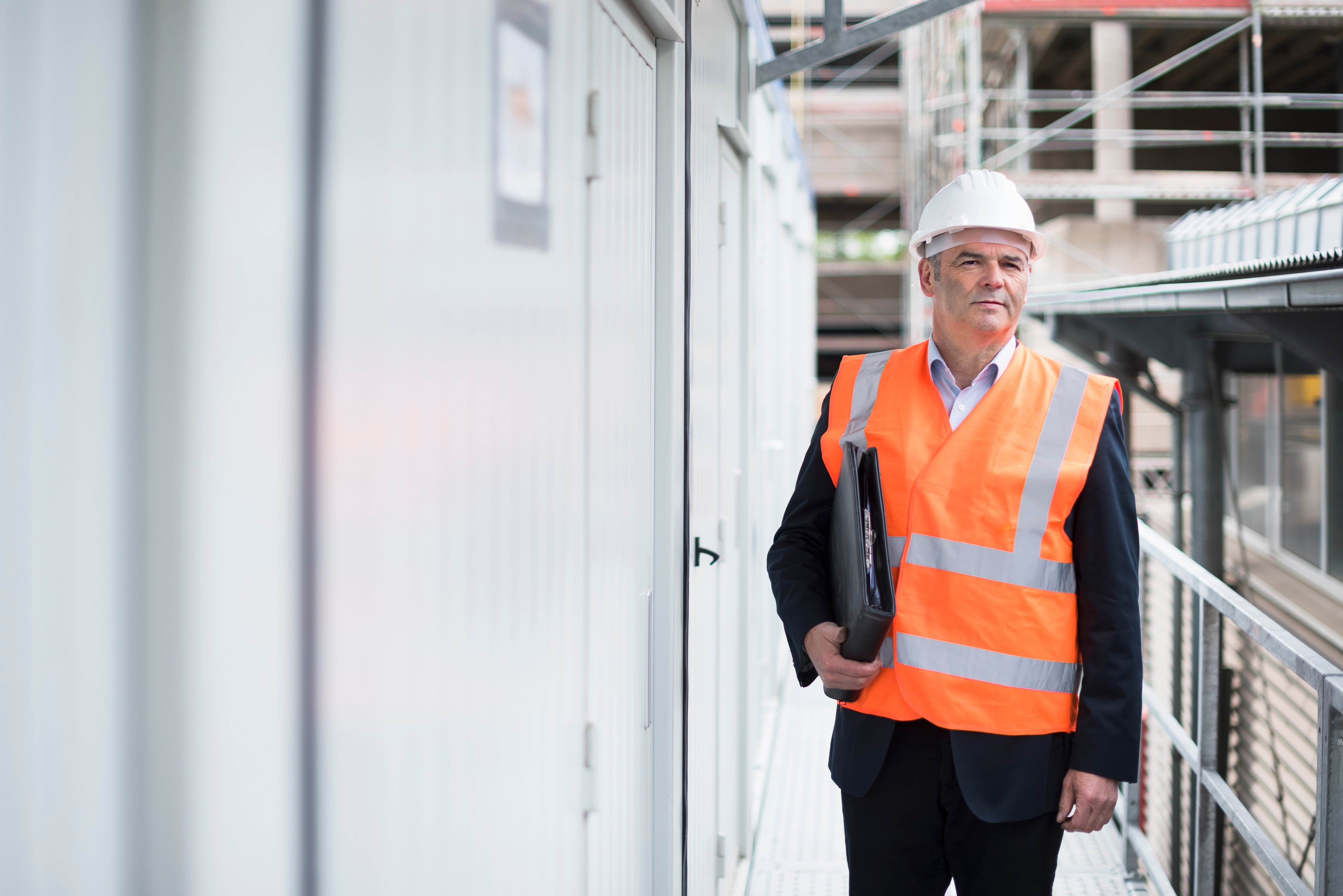 man-with-documents-wearing-safety-vest-on-construc-2023-03-23-23-22-58-utc