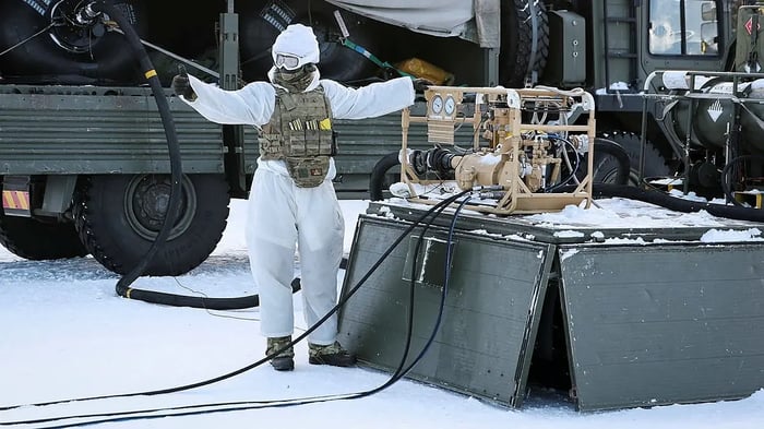 A UK soldier in winter camouflage operating fuel pumping equipment during an Arctic military exercise