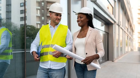 Male and female building engineering professionals discussing plans on site
