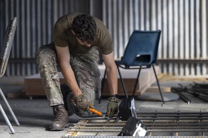 A Royal Engineers soldier in camouflage working on a structural steel framework during a construction task