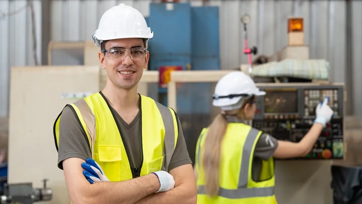 Young engineers in hi-vis vests and hard hats training in a building services engineering workshop