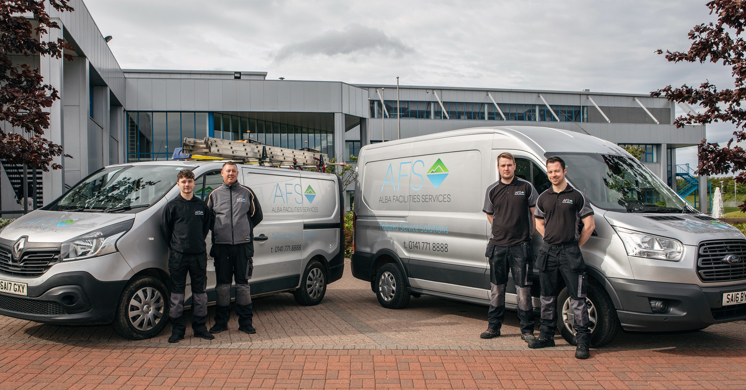 Alba Facilities Services team standing in front of company vans and office, representing their shift to a 4-day workweek in facilities management.