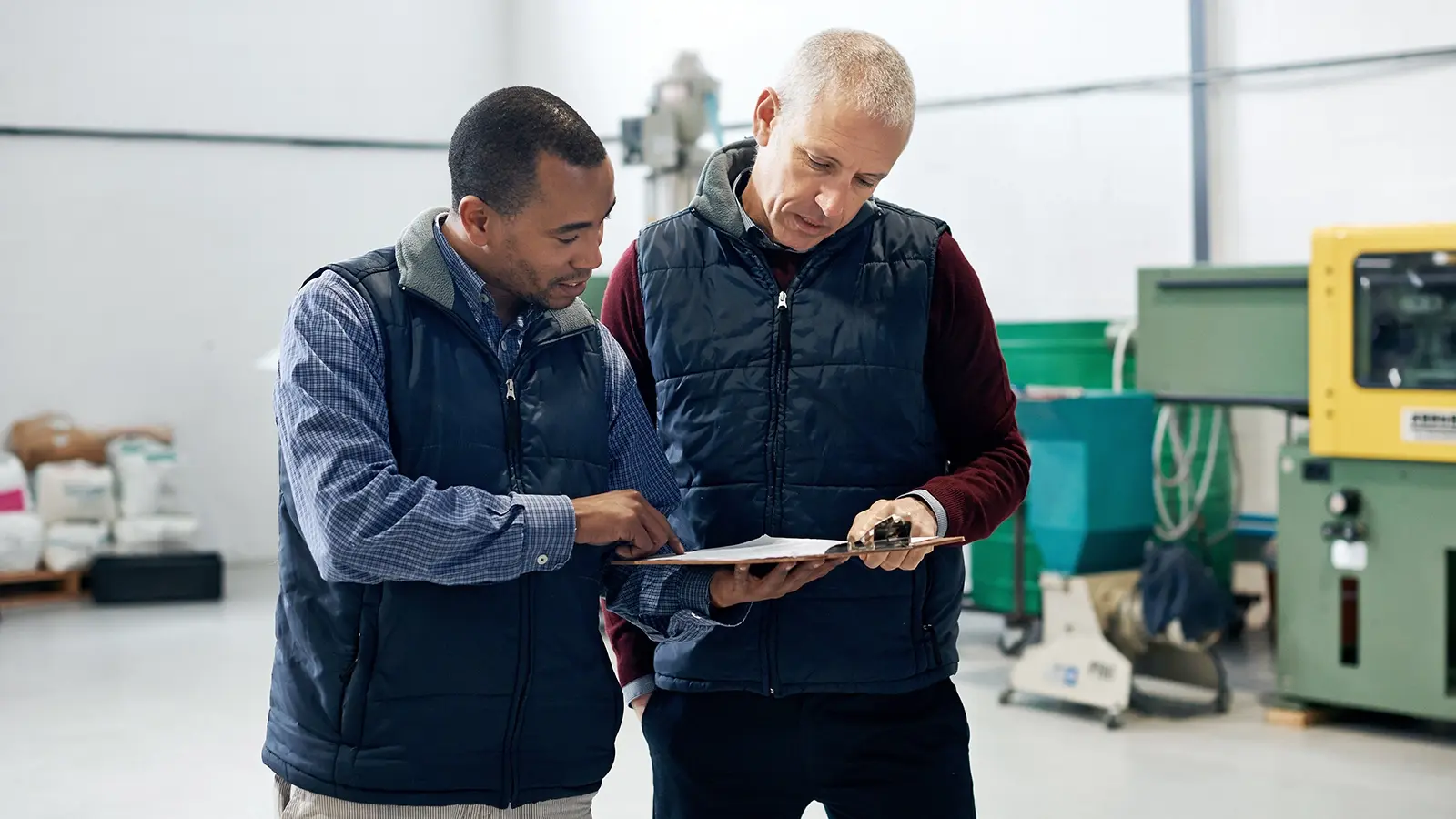 Building services employee reviewing a practical assessment with an assessor in a technical workshop