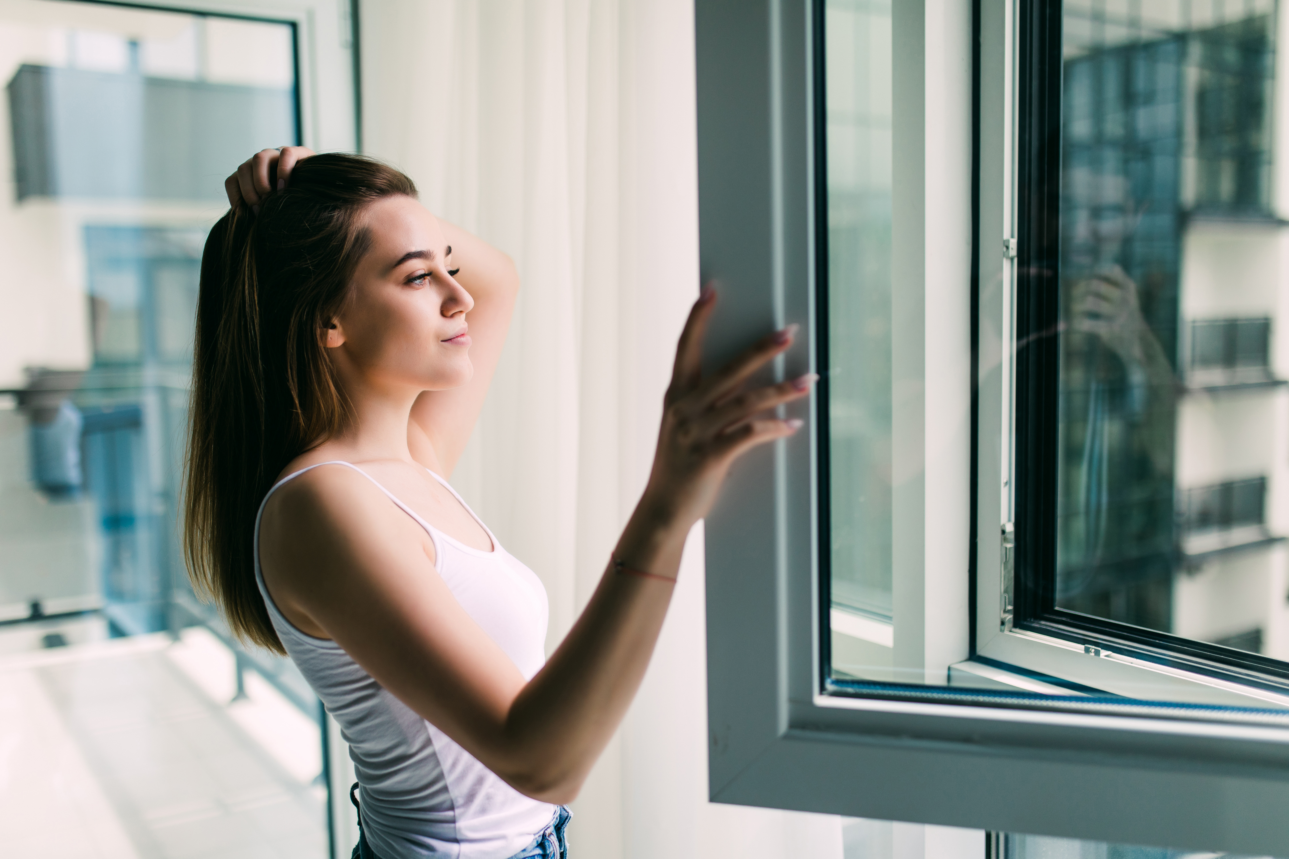Woman opening a window to improve ventilation in her home